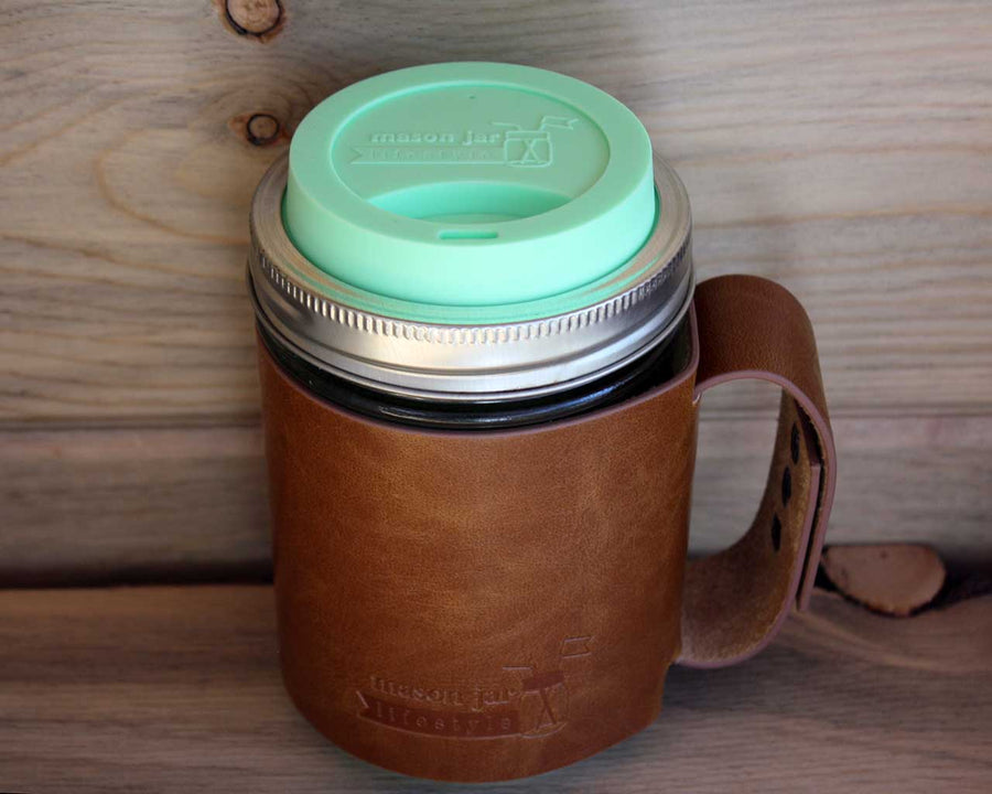 Mint green silicone drinking lid and faux leather sleeve with handle on wide mouth pint Mason jar