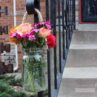 Thick rope handle on wide mouth quart Mason jar with flowers hanging on railing