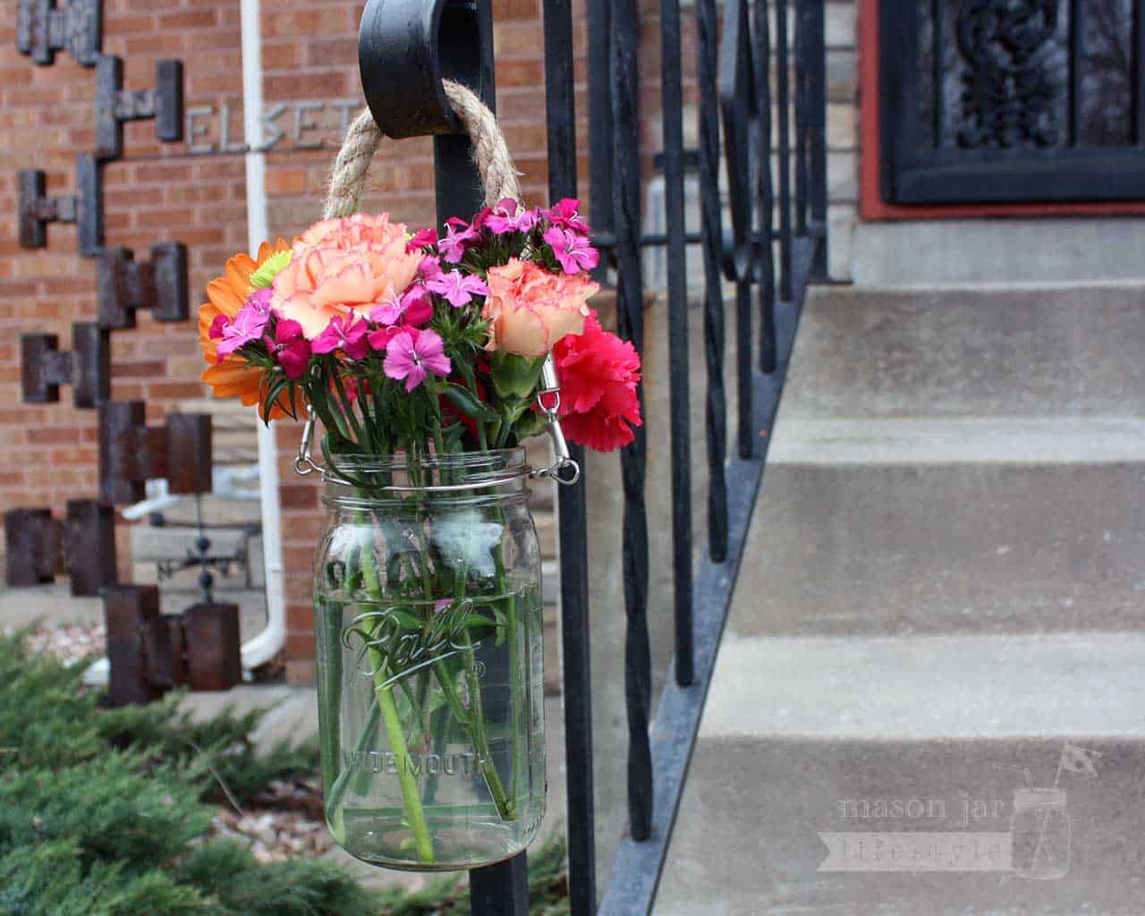 Thick rope handle on wide mouth quart Mason jar with flowers hanging on railing