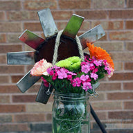 Thin rope handle on wide mouth quart Mason jar with flowers hanging on metal flower