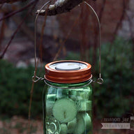 Metal tea light candle holder insert with copper band and stainless steel wire handle on tree branch