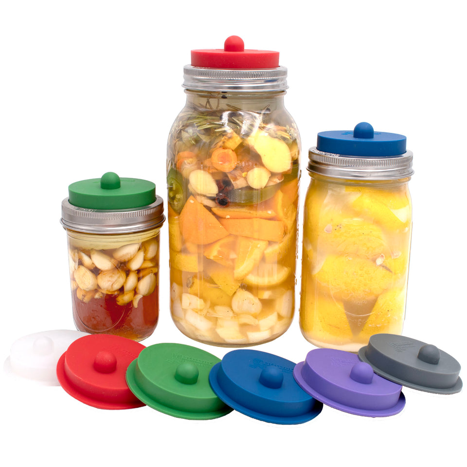 Colorful silicone sealing lids on Mason jars filled with fruit, nuts, and lemon water