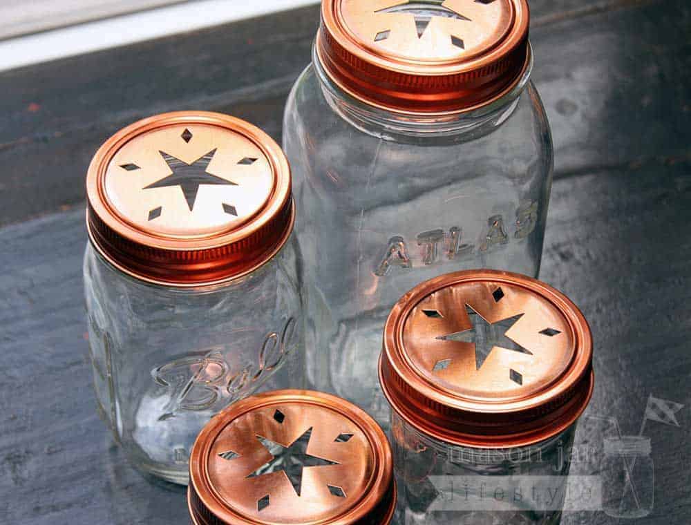 Copper star cutout lids and bands on 4 Ball Mason jars - a 4oz jelly jar, half pint jar, pint jar, and quart jar. Top view.