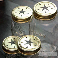 Gold star cutout lids and bands on 4 Ball Mason jars - a 4oz jelly jar, half pint jar, pint jar, and quart jar