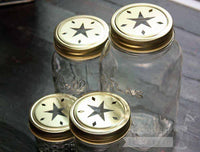 Gold star cutout lids and bands on 4 Ball Mason jars - a 4oz jelly jar, half pint jar, pint jar, and quart jar