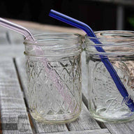 Two half pint Ball jars with pink and blue glass straws