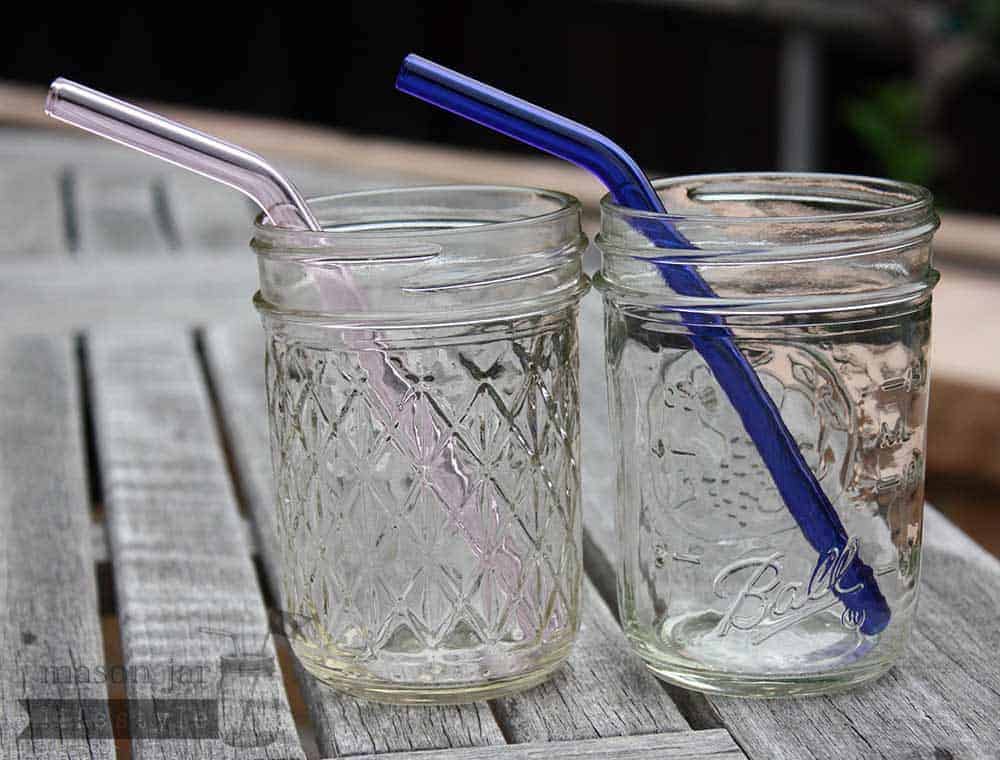 Two half pint Ball jars with pink and blue glass straws