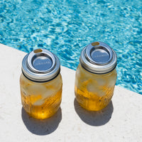 This product is a 2pk, there are two Mason jars next to the side of a pool, with the sip lids on them, and an icy drink inside the jars.