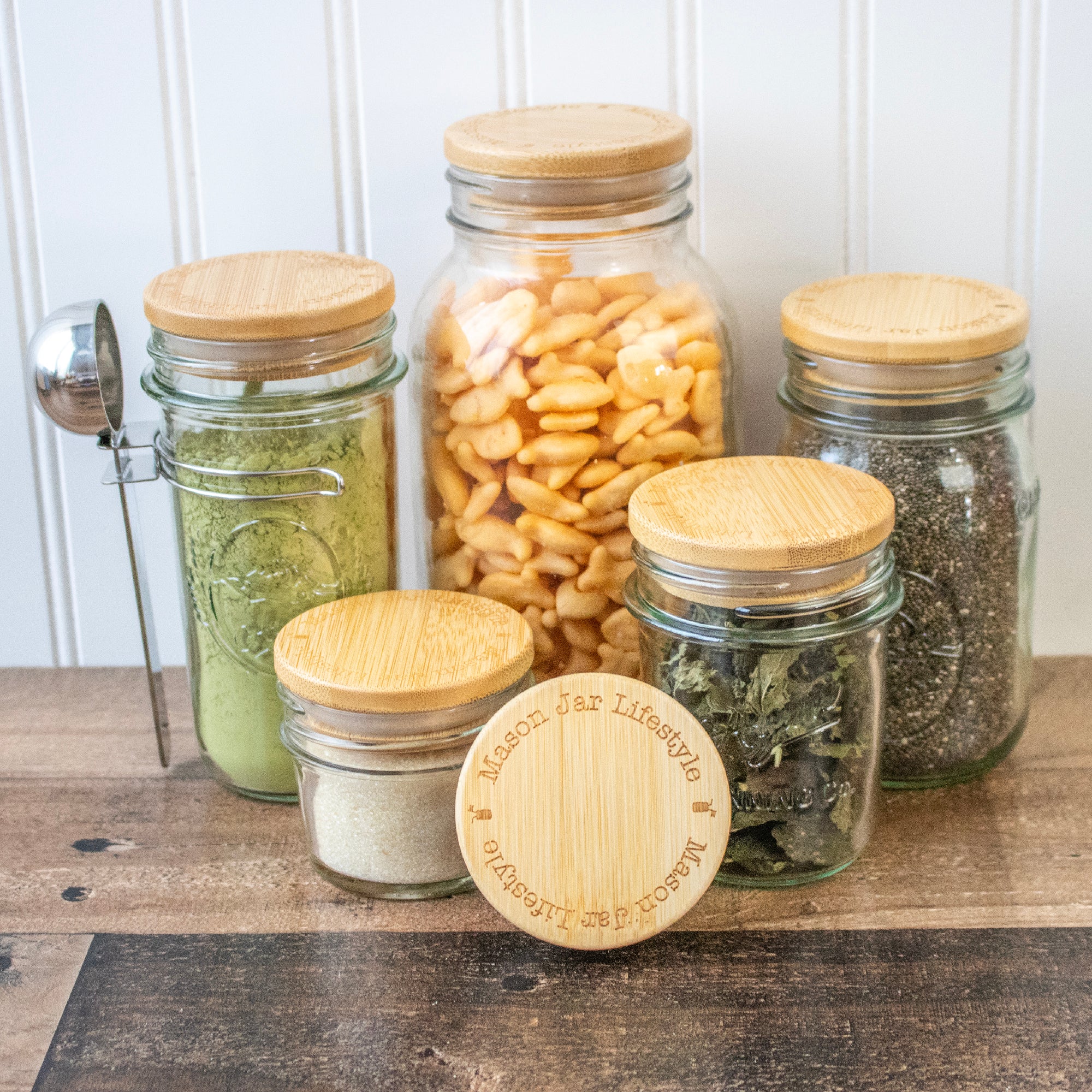 Regular mouth Mason jars with bamboo storage lids: 4oz, 8oz, 16oz, 32oz, and 64oz jars.