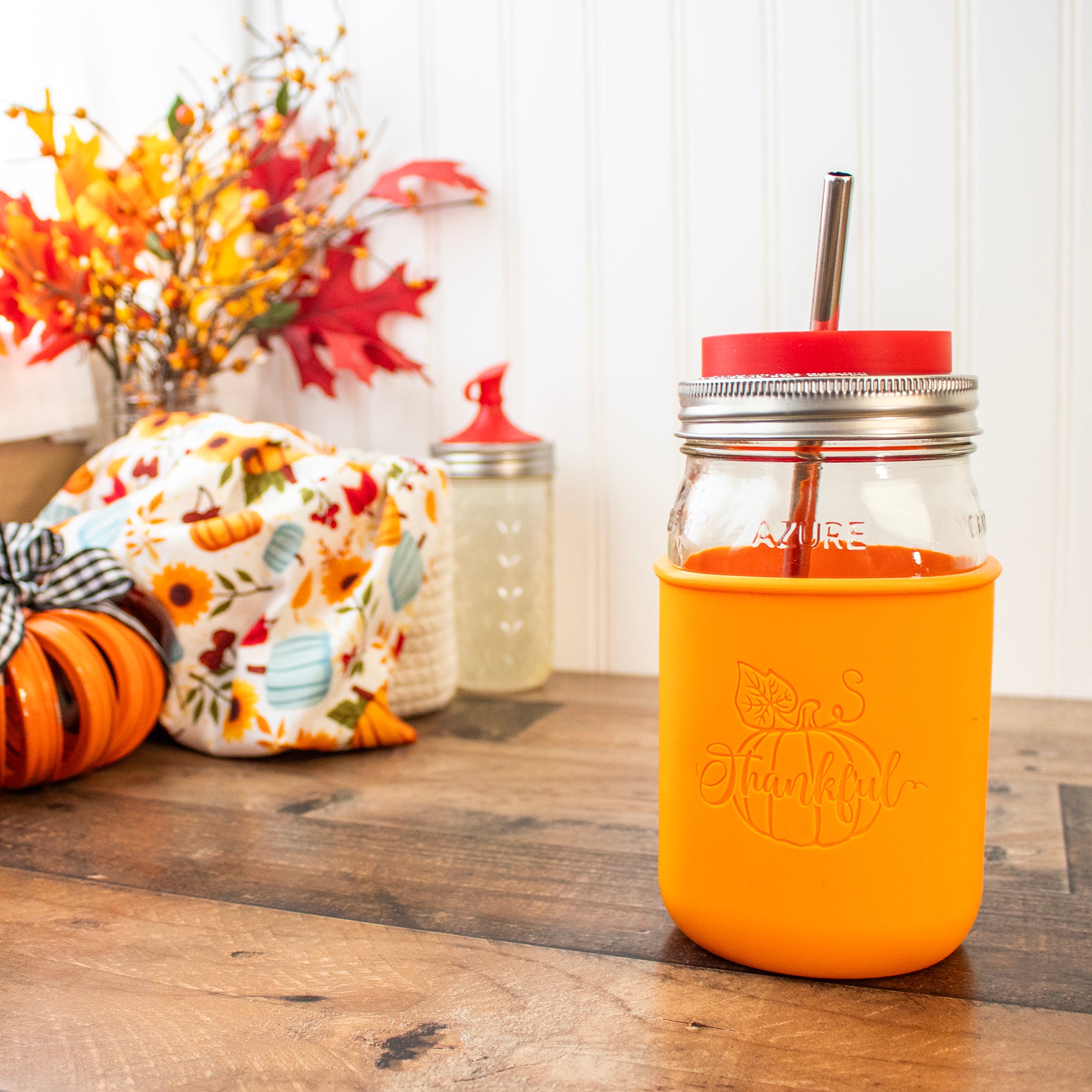 A Quart Mason jar with the "Be Thankful" sleeve on it, with additional accessories: stainless steel straw and silicone straw hole lid.