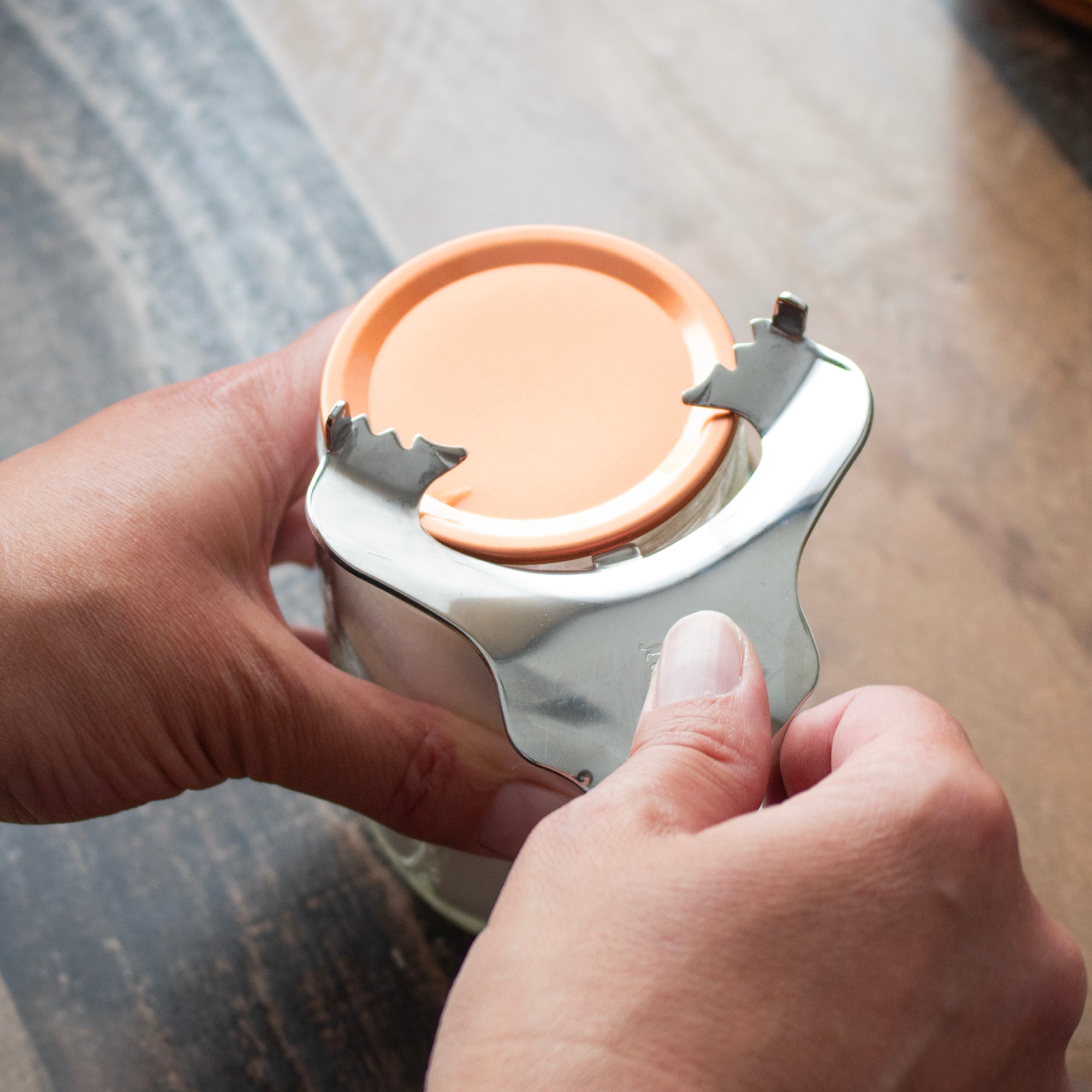 The can opener prying the edge of a flat canning lid.