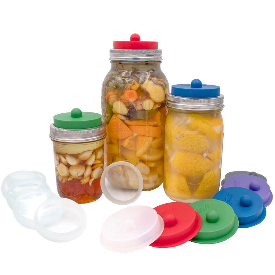 Fermentation starter kit, which includes a silicone fermentation lid, and stainless steel band. They come in 6 colors: charcoal gray, ultra violet, deep blue, leaf green, cherry red, and frost. Shown on three different sized wide mouth Mason jars: half gallon, quart, and pint.