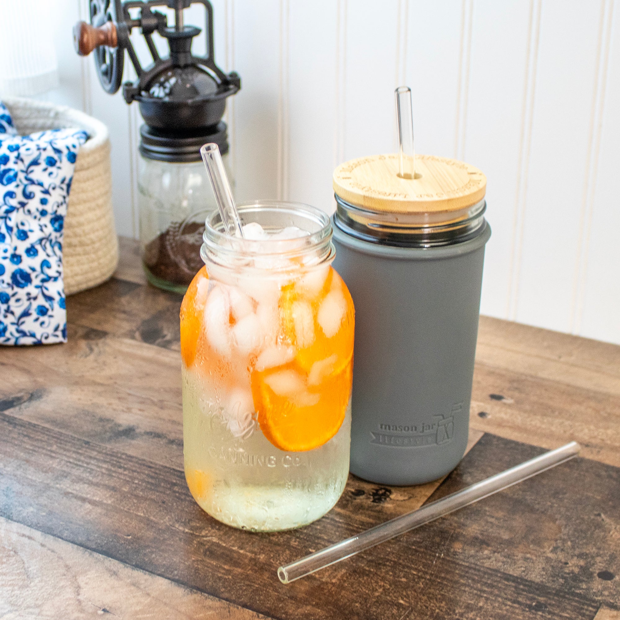 Long glass straws in regular mouth 32oz Mason jar and 24oz Mason jar, one with a bamboo straw hole lid.