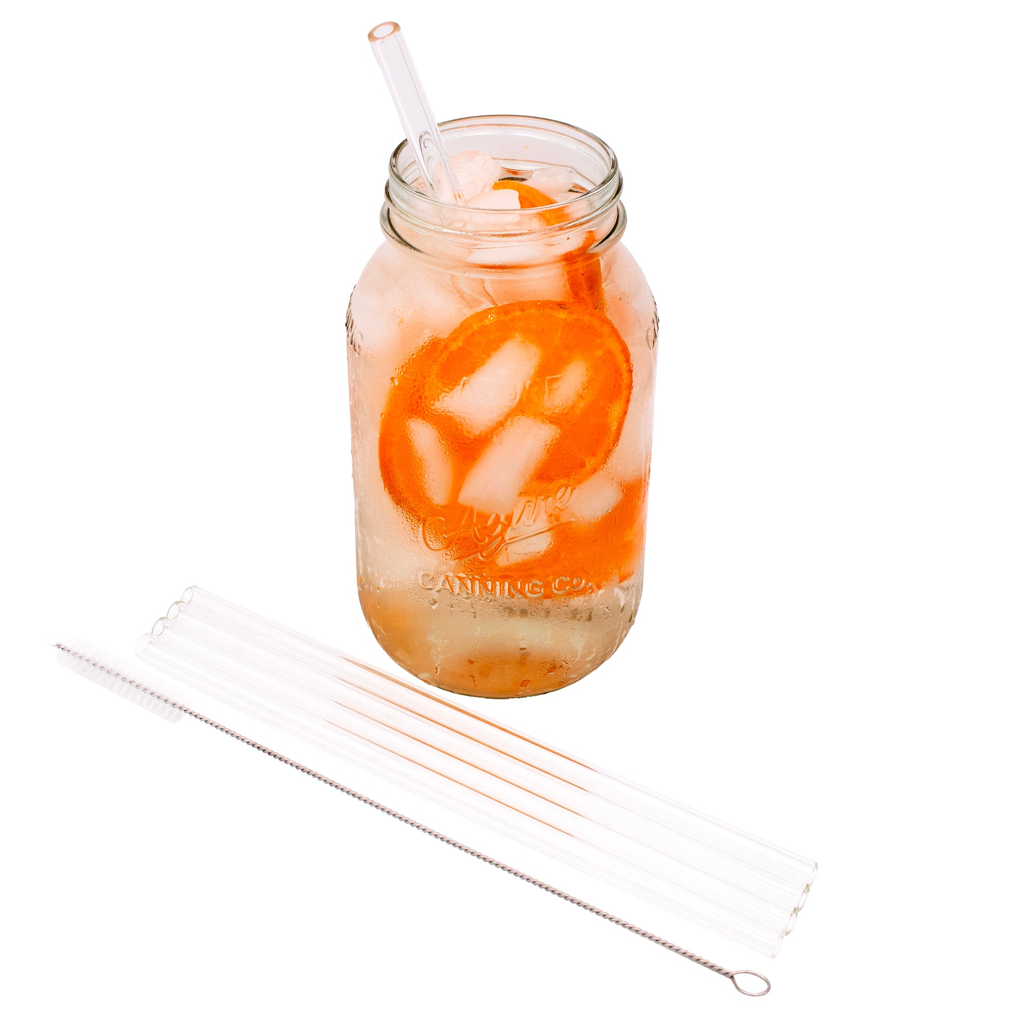 4 pack of short glass straws and the straw cleaner next to it, laying in front of a Mason jar full of water and oranges, with a glass straw in it.