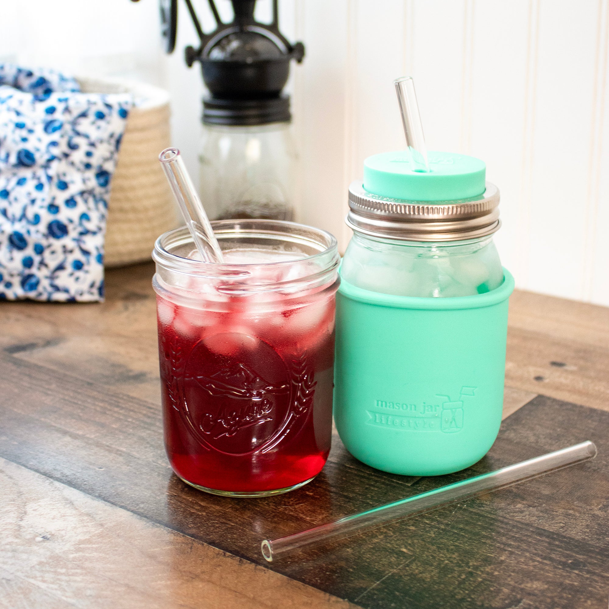 Medium glass straws in regular and wide mouth 16 oz Mason jars, one with a silicone straw hole lid.