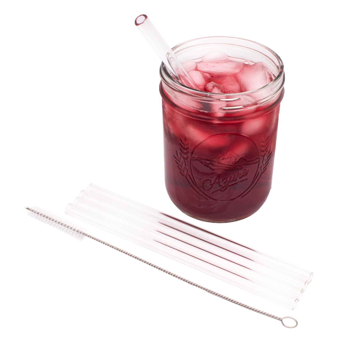 4 pack of medium glass straws and the straw cleaner next to it, laying in front of a Mason jar full of juice, with a glass straw in it.