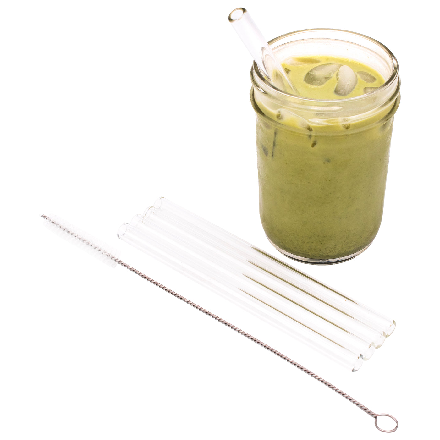 4 pack of short glass straws and the straw cleaner next to it, laying in front of a Mason jar full of matcha, with a glass straw in it.