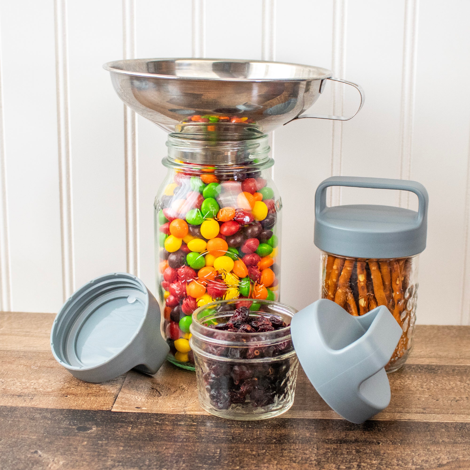 Canister lids on regular mouth Mason  jars, next to a jar with a funnel in it.