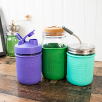 Example of the Mason jar engraved sleeves on quart sleeves and wide mouth sleeves, with pour and store lid, cork lid, and stainless steel straw hole lid with straw.