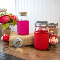 Two Mason jar quart sleeves with lids  with Valentine's designs. The "Sweetheart" design in berry pink, on a sleeve on a regular mouth quart Mason jar. The "I Don't Need a Valentine" design in cherry red, on a wide mouth quart Mason jar.