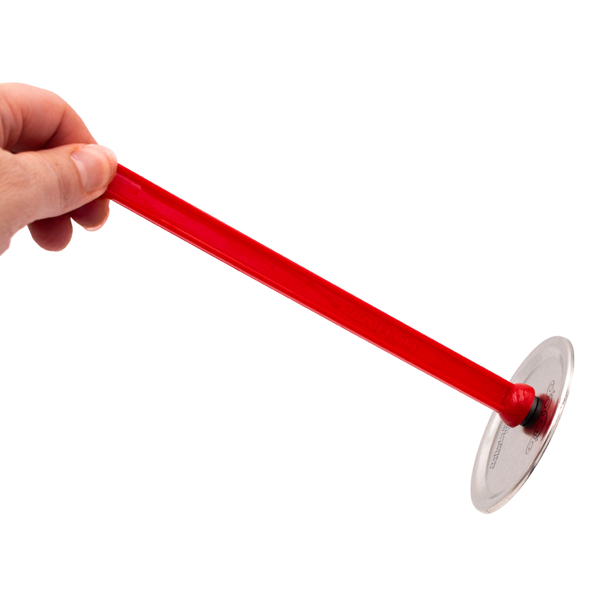 A hand holding a magnetic jar lid lifter, lifting a tin canning lid by the magnet on the bottom of the handle