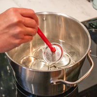 One lid being lifted out of boiling water with the magnet, instead of with tongs.