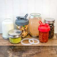 Wide mouth and regular mouth silicone sealing rings, amongst a bunch of jars that have lids with sealing rings in them.