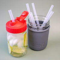 Silicone straws in pint Mason jars, against a green background to show that the material is translucent.