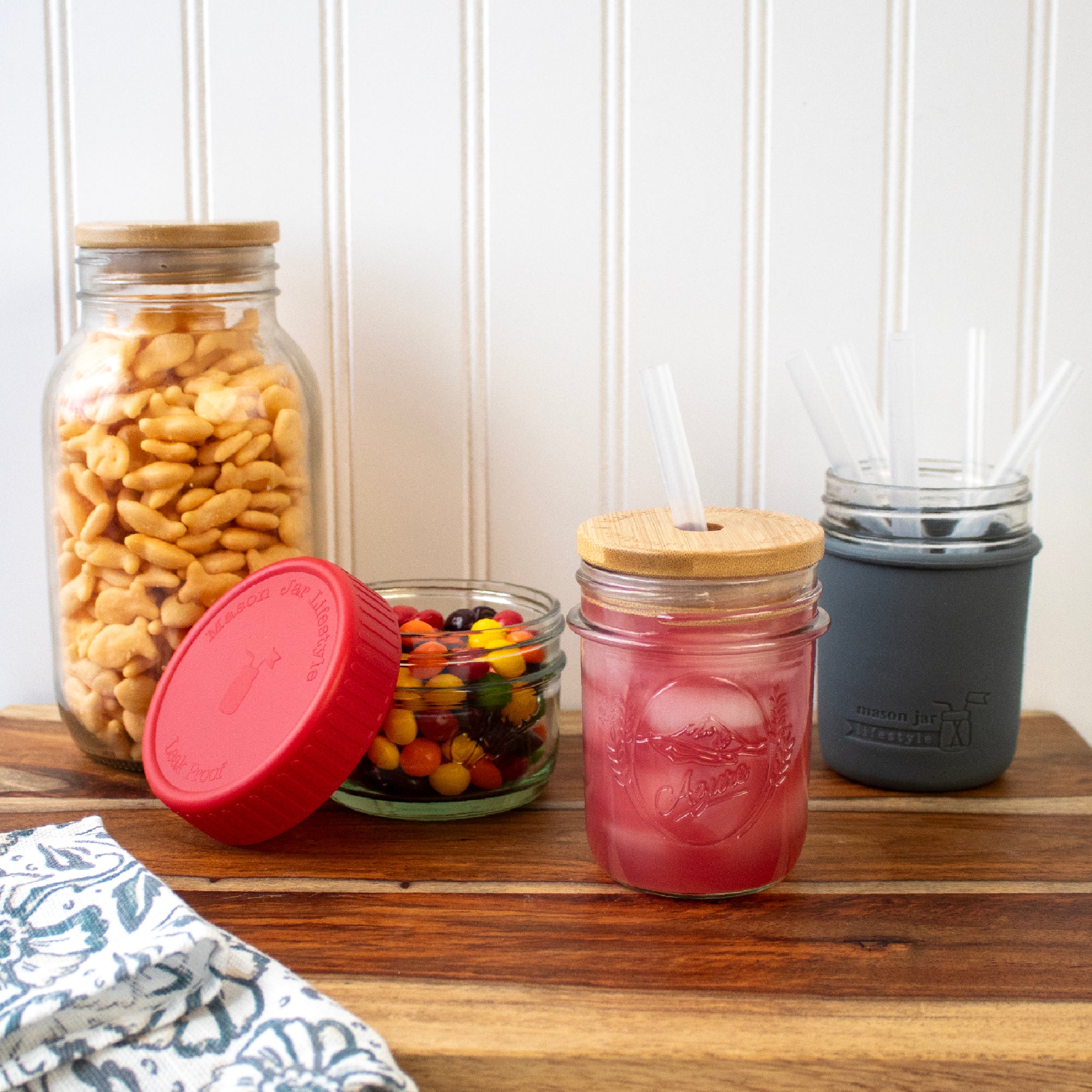 Mason jars with silicone straws, and plastic storage lids, and bamboo storage lids.
