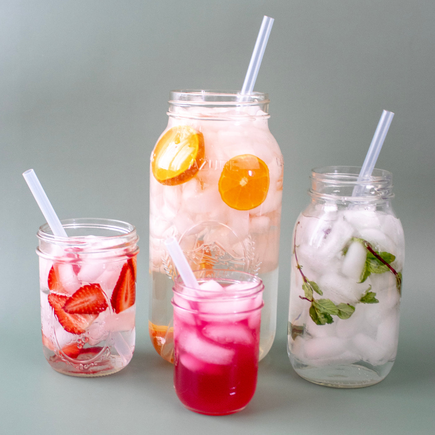 Four different sized Mason jars with four different sized silicone straws in them. A half gallon jar with an extra long straw, a quart jar with a long straw, a pint jar with a medium straw, and a 8oz jar with silicone straw.