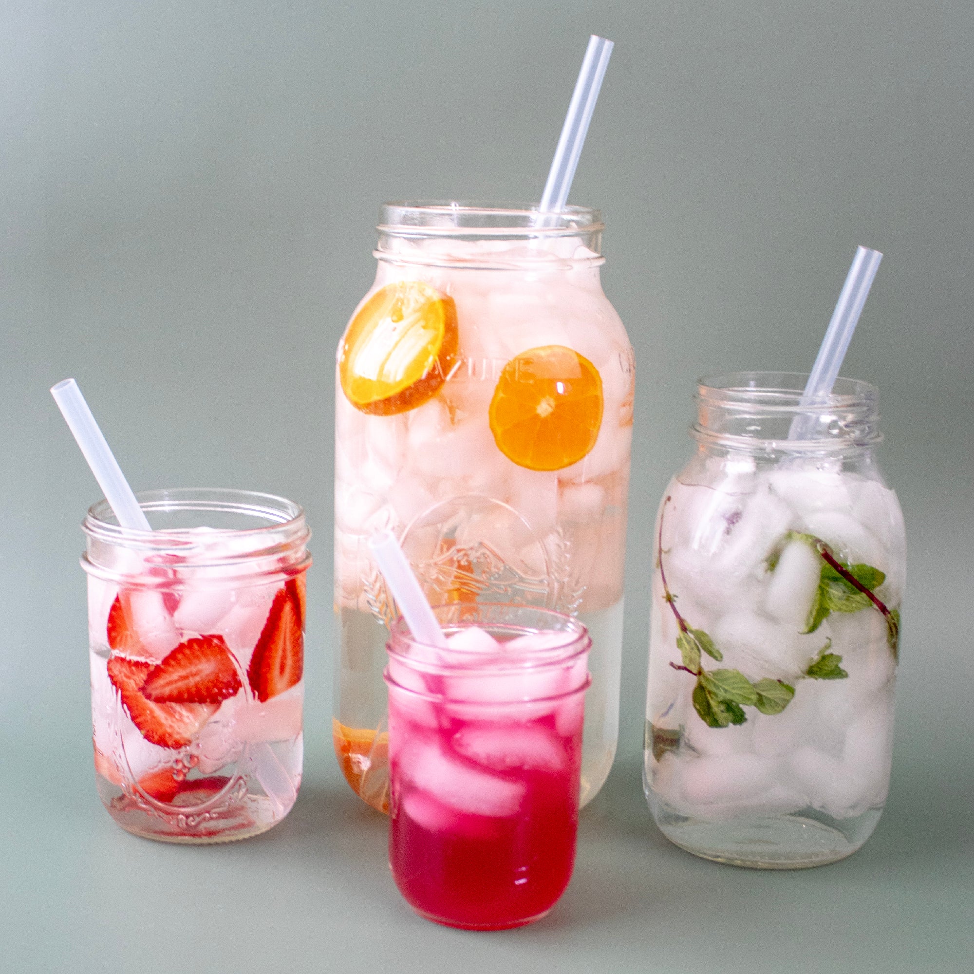 Four different sized Mason jars with four different sized silicone straws in them. A half gallon jar with an extra long straw, a quart jar with a long straw, a pint jar with a medium straw, and a 8oz jar with silicone straw.