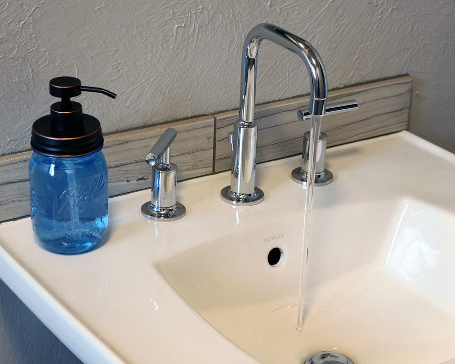 Oil rubbed bronze soap pump dispenser lid kit on blue Ball Mason pint jar on sink with running water