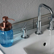 Vintage copper soap pump dispenser lid kit on blue Ball Mason pint jar on sink with running water