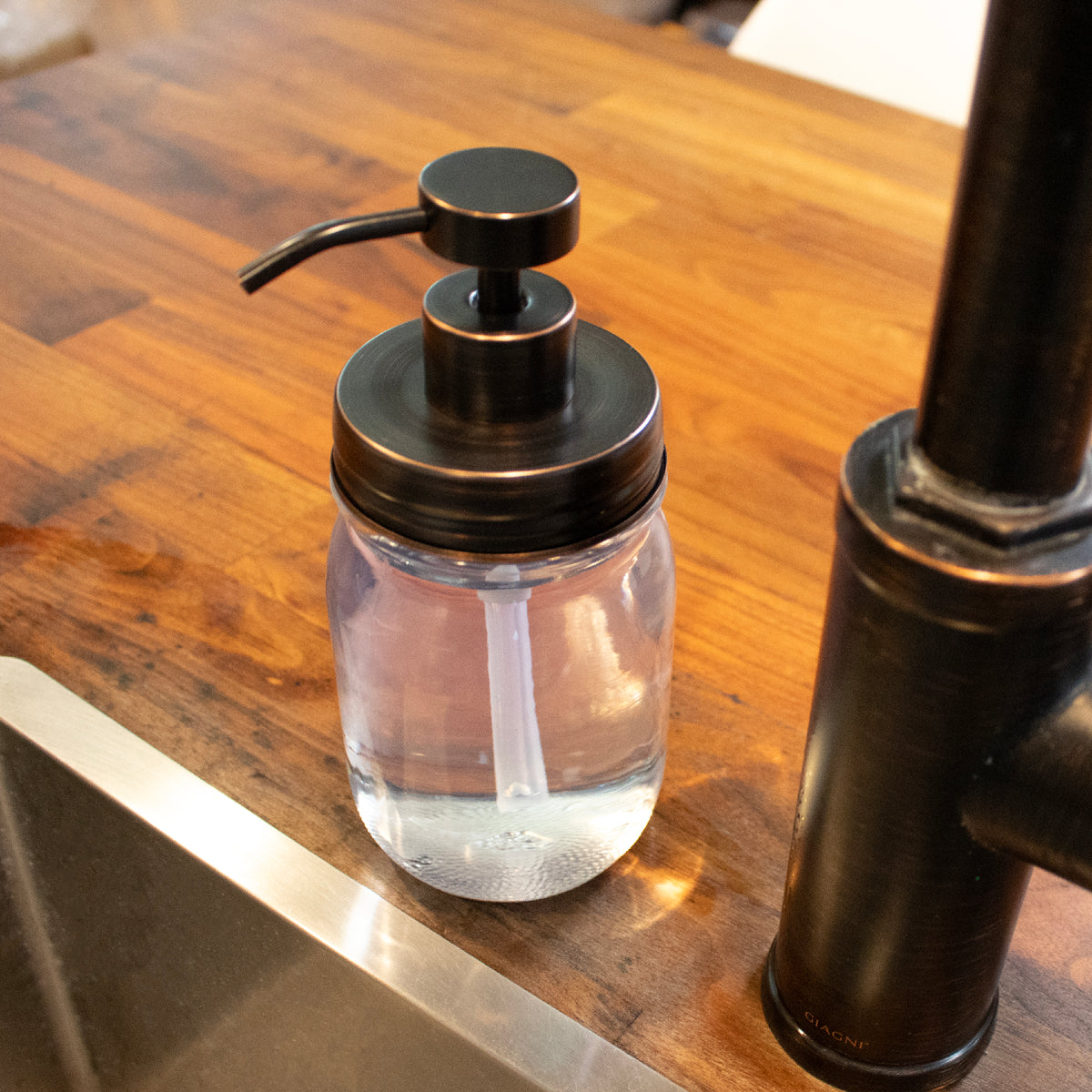 The soap pump next to a kitchen skin, matching the fixture's oil rubbed bronze finish.