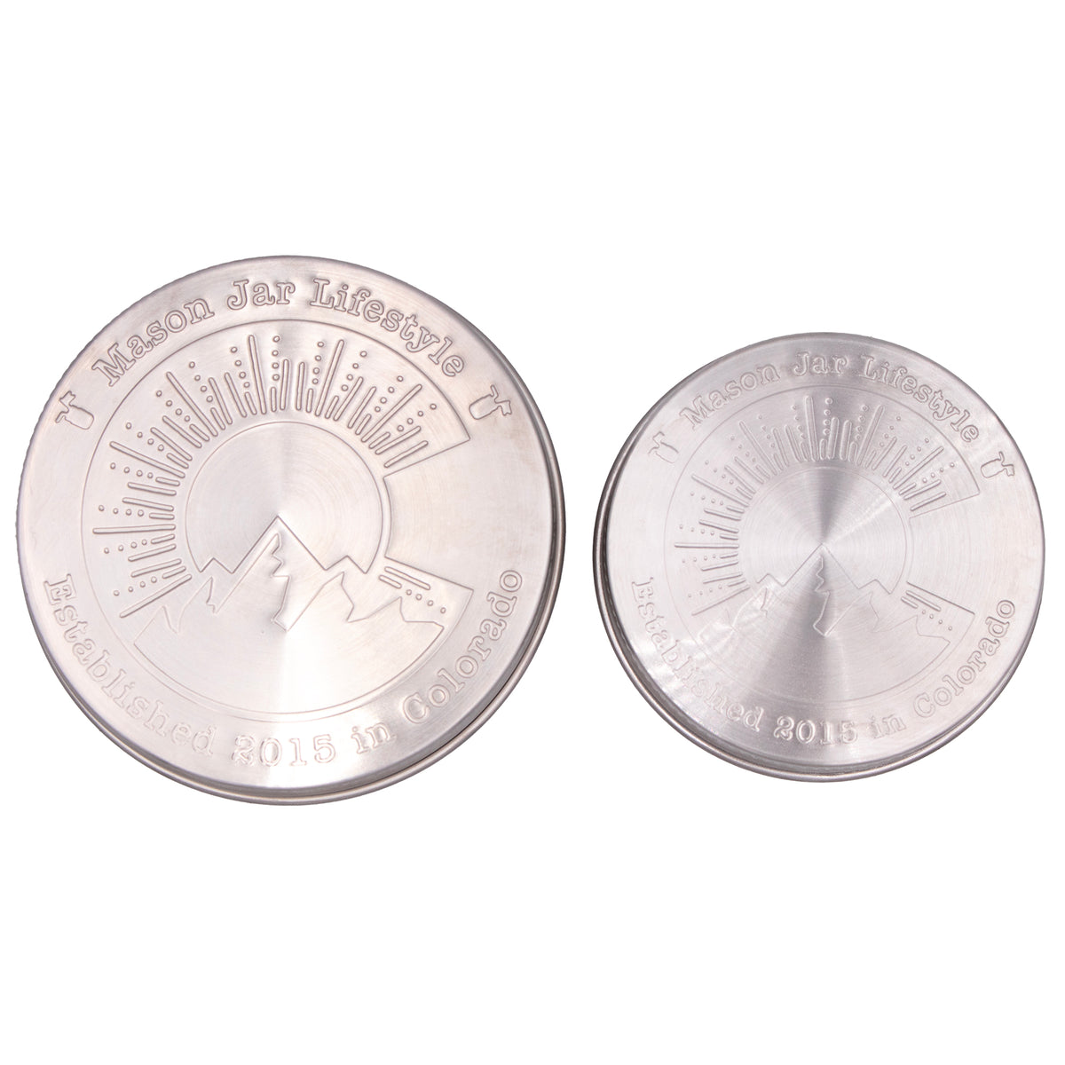 Two stainless steel storage lids for Mason jars up close, showing off the design that says "Mason Jar Lifestyle" and "Established 2015 in Colorado" with a big "C" in the middle with a silhouette of a mountain, a sun, and sun rays.