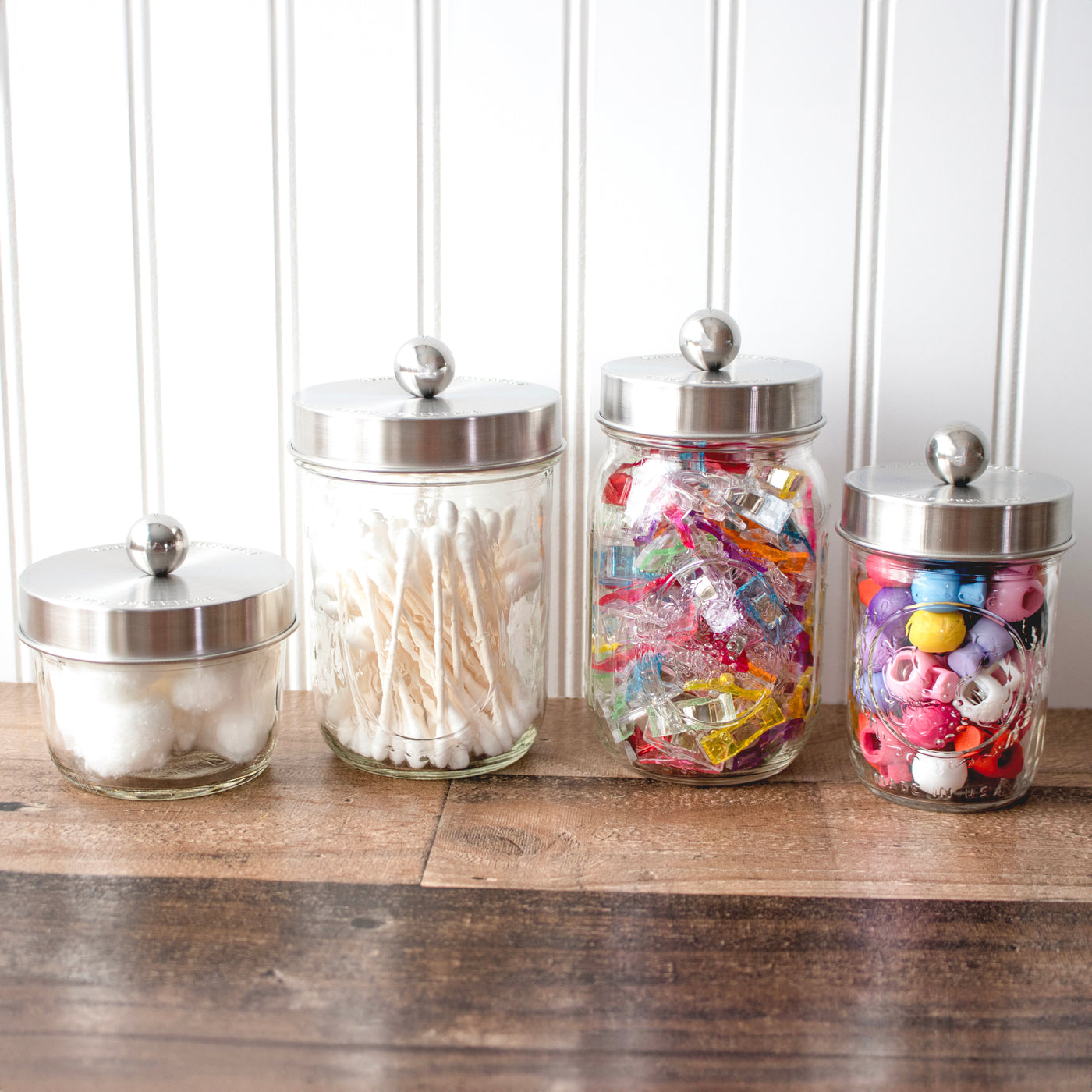The apothecary lids on 8oz and 16oz jars, with non perishables inside: cotton balls, q-tips, and craft supplies.