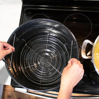Hand lowering the water canning rack into the pot by it's two handles.