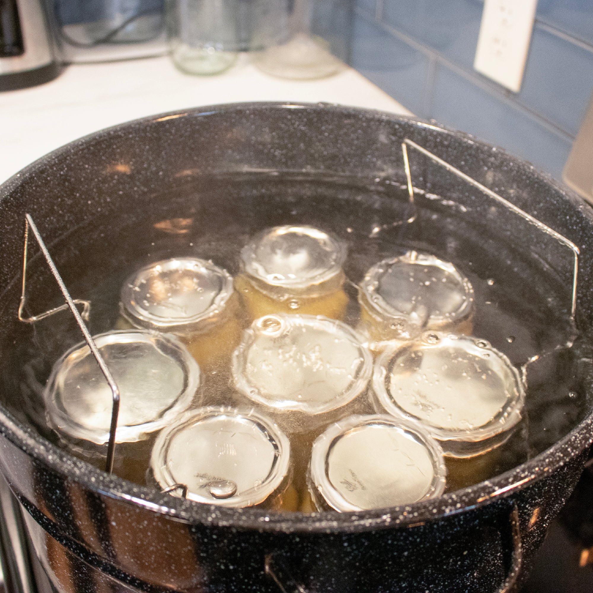 Jar submerged under boiling water, with the handles sticking above the water line.