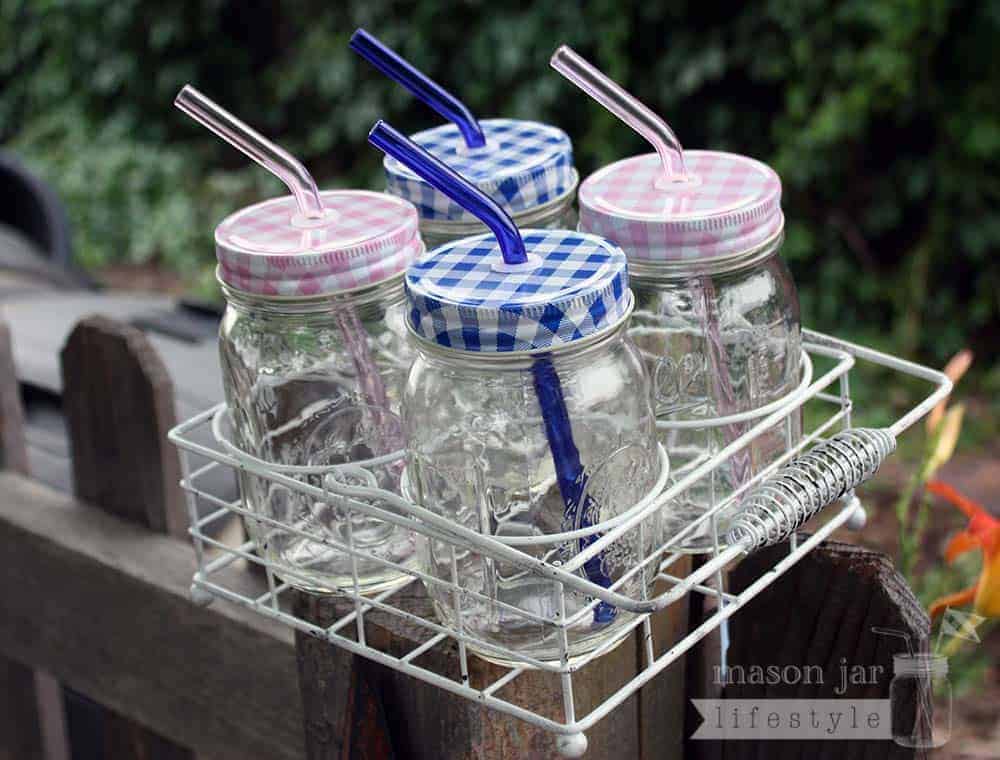 Carrying caddy for 4 pint jars with pink and blue glass straws and gingham lids