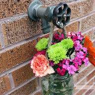 Thin rope handle on wide mouth quart Mason jar with flowers hanging on water faucet