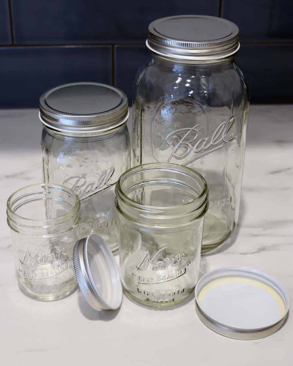 Shiny silver storage lids on half pint, pint, quart, and half gallon Ball and Kerr Mason jars