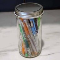Wide mouth shiny silver storage lid on Pint & Half Ball Mason jar with pens