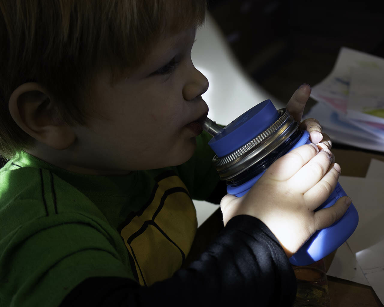 Boy drinking from half pint 8oz Mason jar with silicone straw, sleeve, and lid