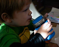 Boy drinking from half pint 8oz Mason jar with silicone straw, sleeve, and lid