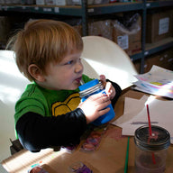 Boy painting and drinking from half pint 8oz Mason jar with silicone straw, sleeve, and lid