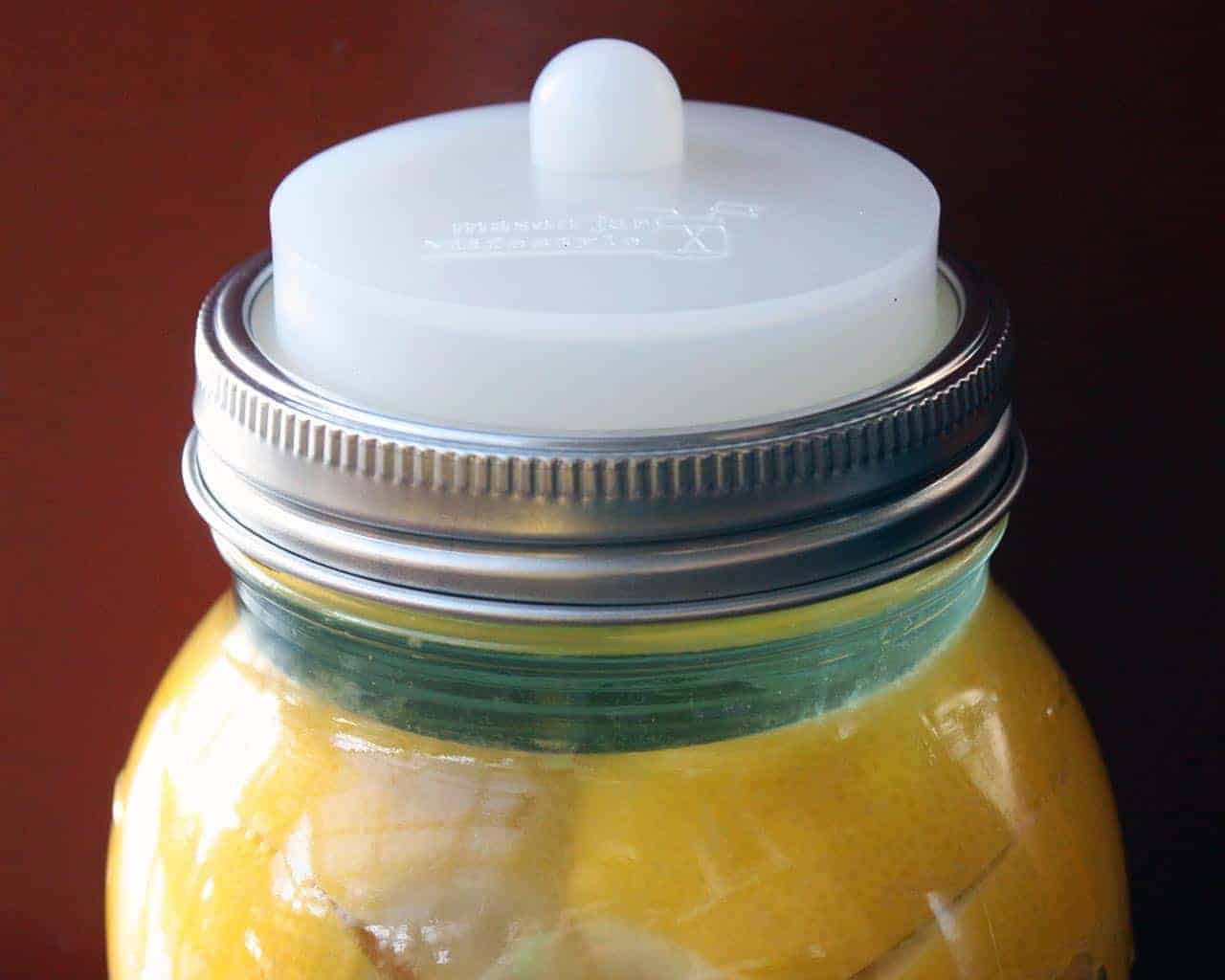 Clear silicone fermentation valve lid with Moroccan preserved lemons and tempered glass fermentation weight