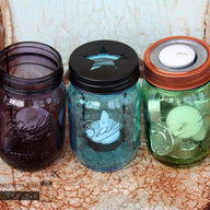 Three types of tea light candle holders on green, blue, and purple Ball Mason jars on rusty chair