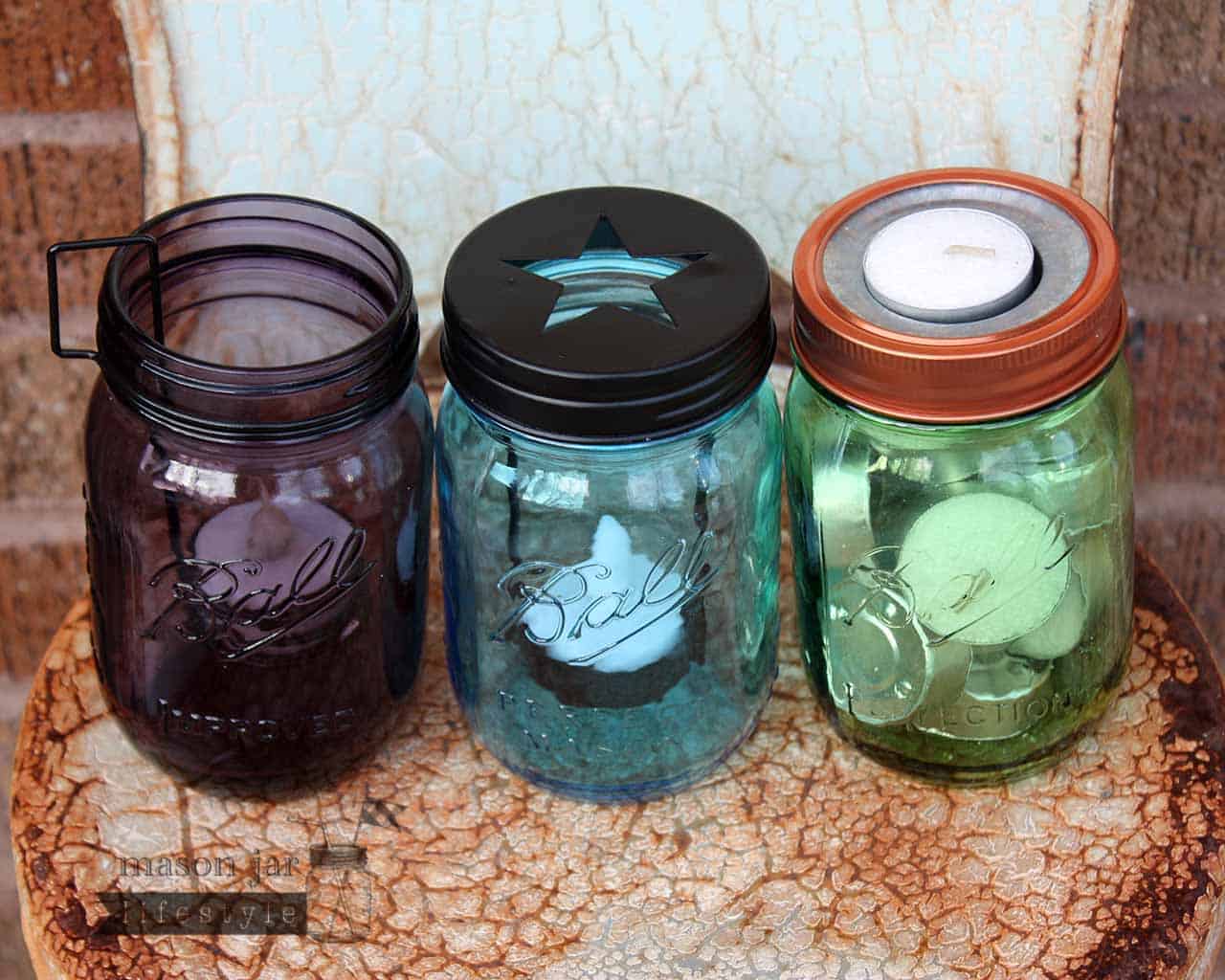 Three types of tea light candle holders on green, blue, and purple Ball Mason jars on rusty chair