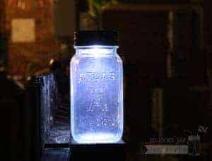 Solar light lid on Atlas Mason jar on fence post at night