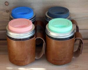 Four wide mouth pint Mason jars with leather sleeves and silicone drinking lids